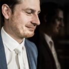 Bräutigam vor Glasschrank mit MiKe's Hochzeitsfotograf